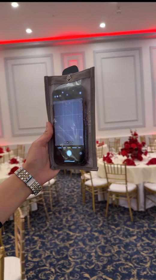 Guest holding a phone inside a Notography case with the camera covered at a reception