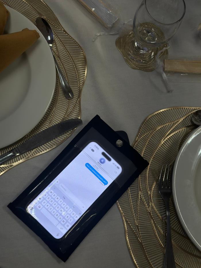 Phone in a Notography case on a set dinner table during a private event